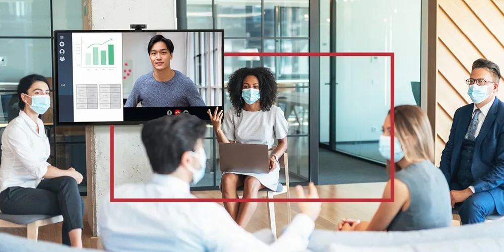 a woman giving a presentation in a huddle space in front of coworkers while a male co-worker is on the ViewBoard display remotely