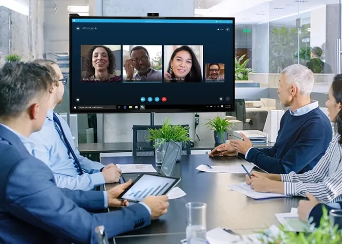 a group of people around a conference table address people joining the meeting remotely through the ViewBoard display