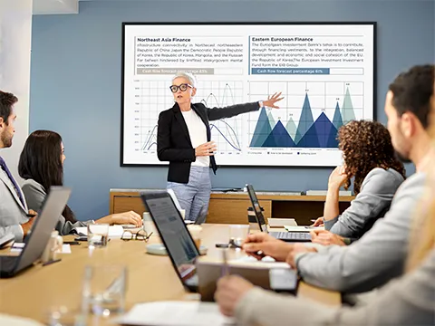 a businesswoman leading a meeting with the aid of large format screens