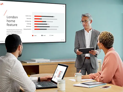 two screens on the wall of a conference room