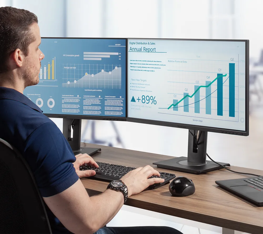 Man working on spreadsheets and reports on a dual VG2756a-2k monitor set up