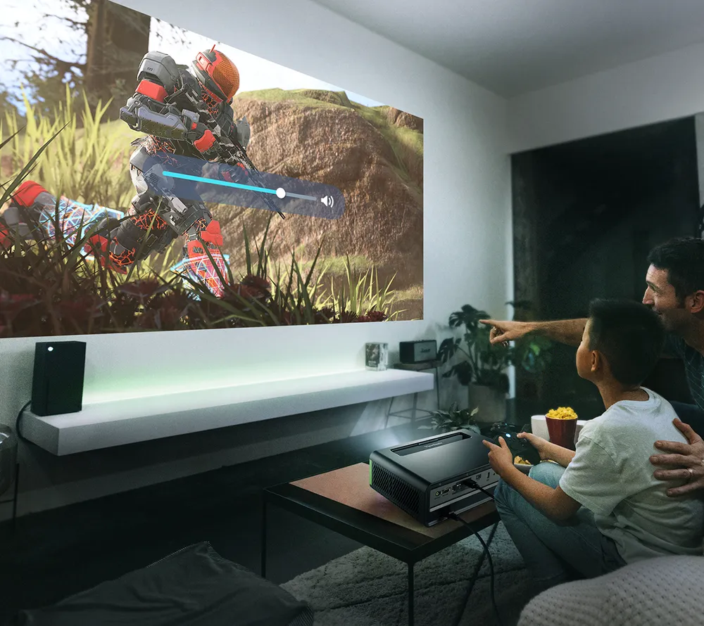 Father and son sitting on a couch playing a game on Xbox using the X2-4K projector
