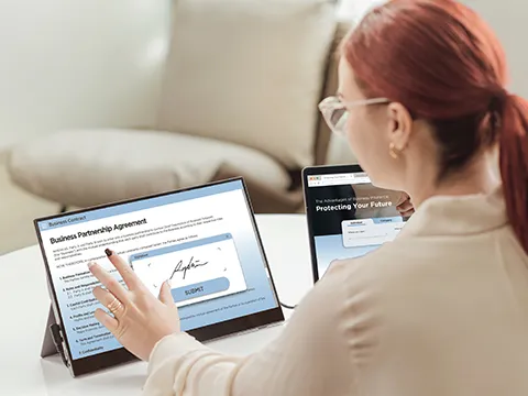 a woman working on a touch screen monitor connected to a laptop