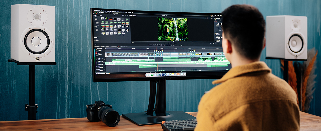 a man sits at an ultrawide monitor with a video timeline in front of him