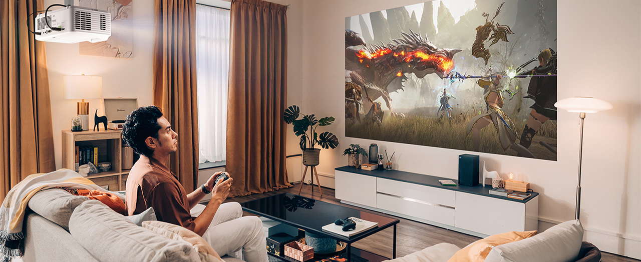 man sitting on a couch playing a video game with video from a projector