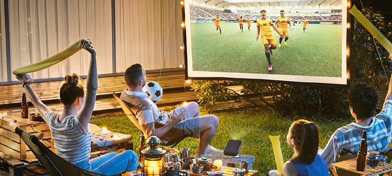 people watching a sports game on a projector outside