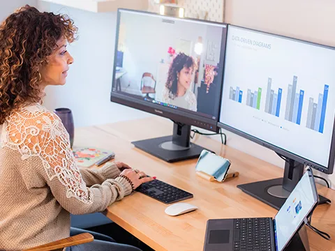 a woman on a video call looking at a graph on her secondary display