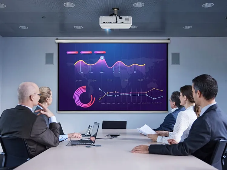 a group of businesspeople in suits around a conference table look at a charts and graphs projected on the wall