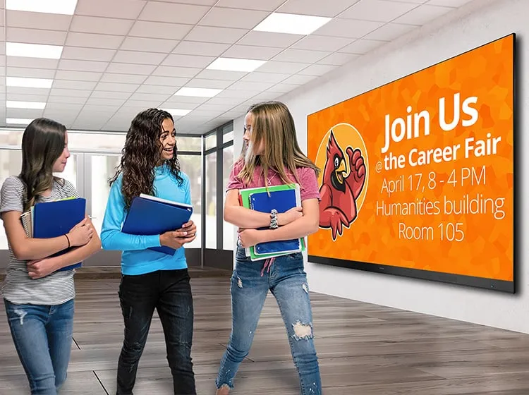 middle schoolers walking through the hals of a school wth a large format display in the background advertising a career fair.